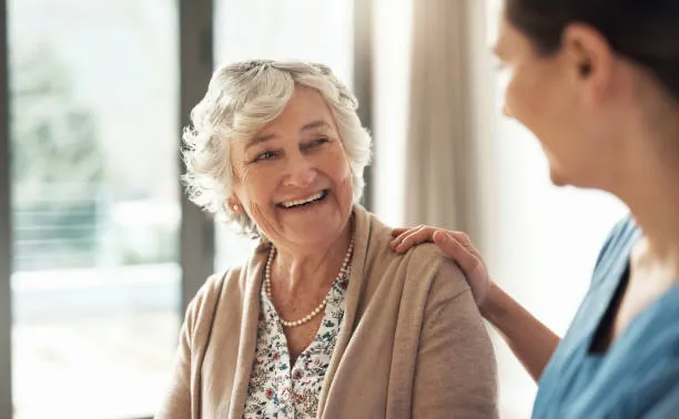 A Twinkling Hearts caregiver smiling warmly with an elderly woman at home